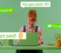 Woman with ginger hair looking happy at her green laptop