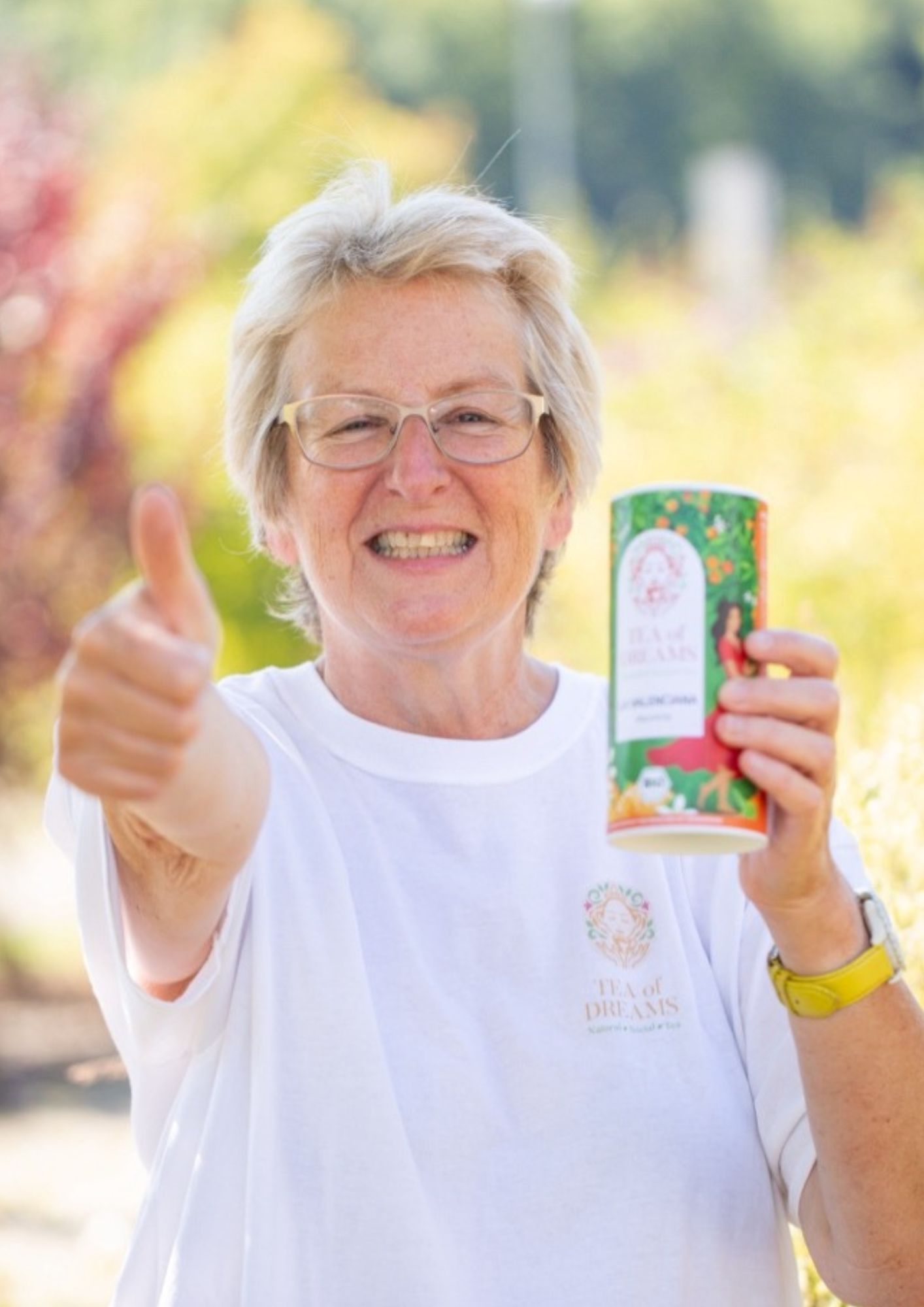 Mitarbeiterin von Tea of Dreams lächelt mit Teedose in der Hand