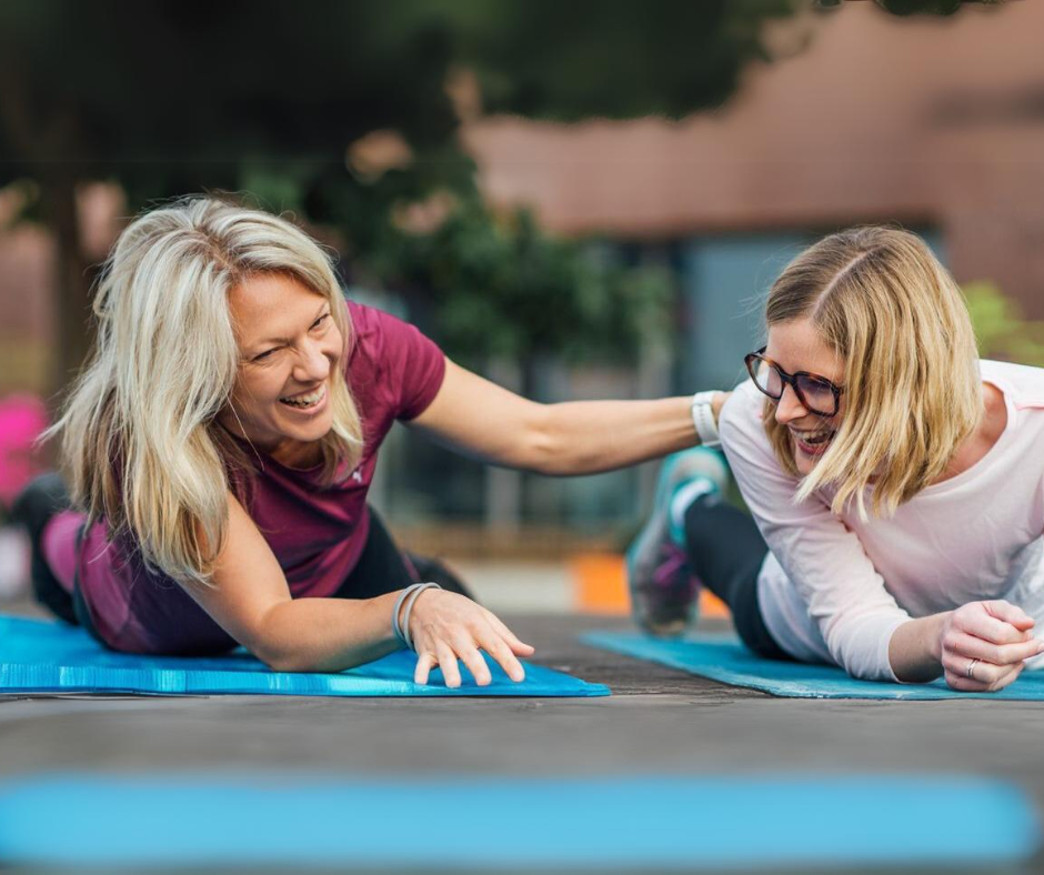 Vanessa Werner, Fitness- und Ernährungsexpertin, liegt lachend auf der Fitnessmatte mit einer Kundin